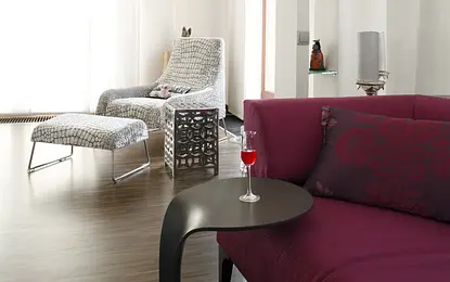 Wnętrze salonu z fioletową kanapą, drewnianą podłogą i dekoracjami eklektycznymi.