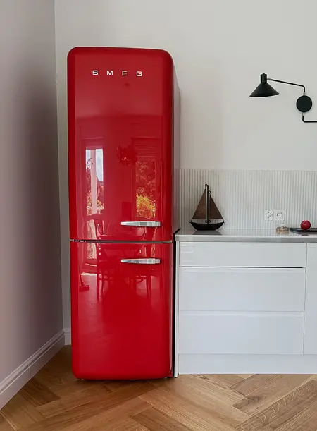 Eklektyczne wnętrze kuchni z czerwonym lodówką SMEG i białymi akcentami, quiet luxury